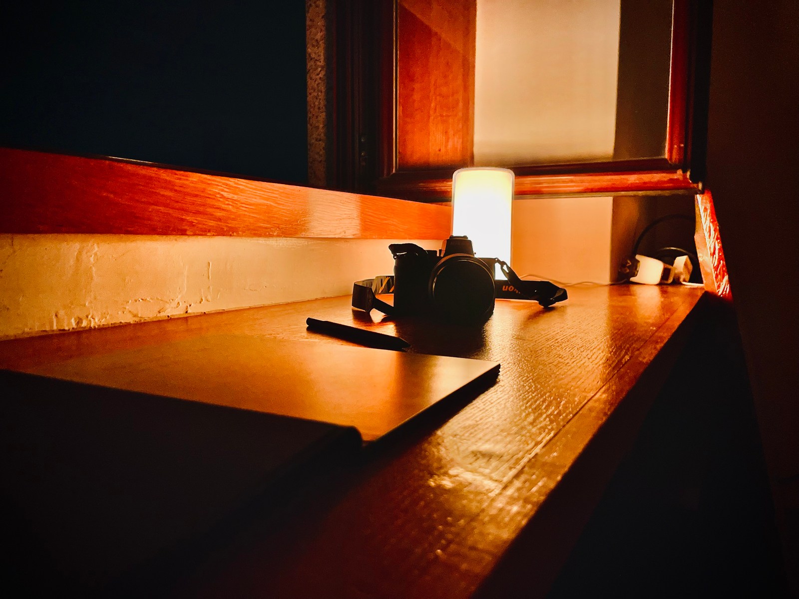 calm, camera, indoor, lamp, notebook, pen, silhouette, solitude, texture, warm light, window